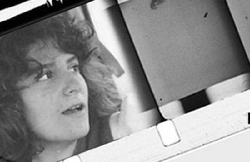 Fotograma de una película antigua en blanco y negro de una mujer joven mirando hacia la cámara con expresión seria.