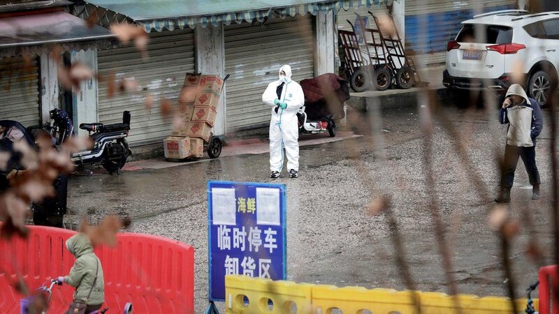 Un trabajador sanitario con traje de protección se encuentra en una calle vacía durante la cuarentena por el coronavirus en Wuhan, China.