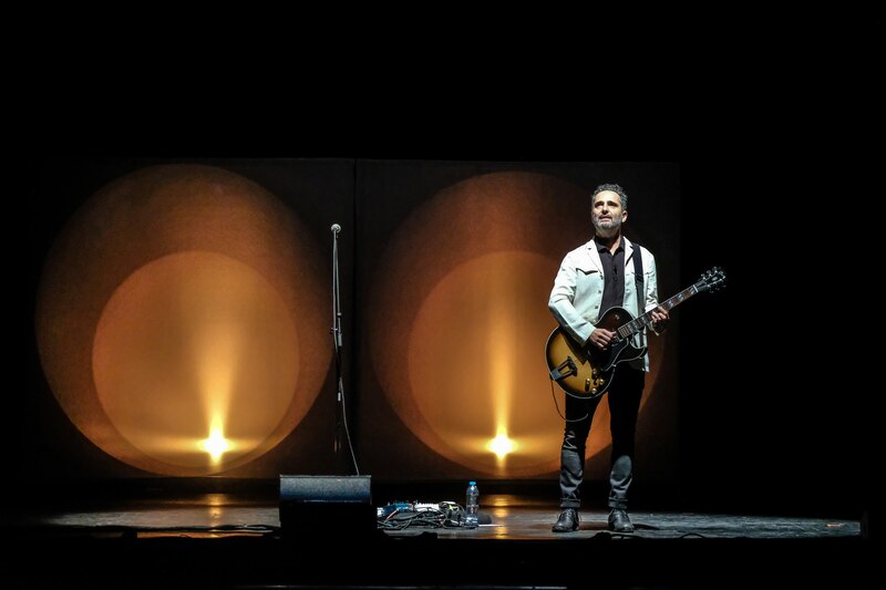 Un músico tocando la guitarra en un escenario.