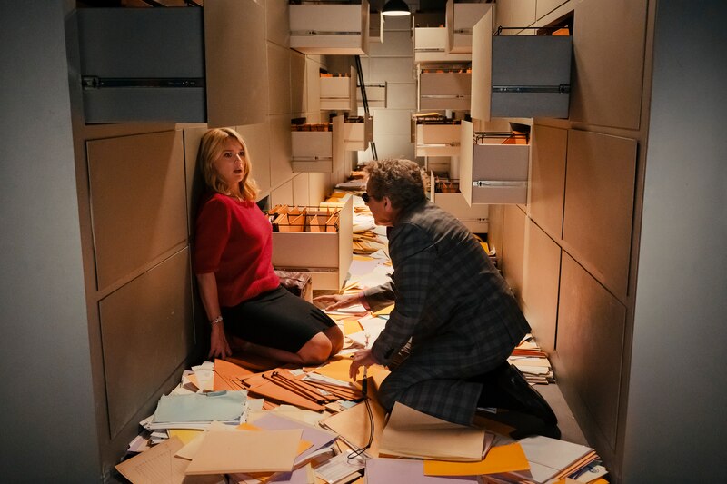 Un hombre y una mujer en un pasillo de oficina con muchos archivadores.