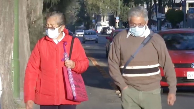 Adultos mayores con mascarillas caminan por la calle