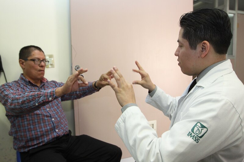 Paciente con discapacidad auditiva se comunica con médico usando lenguaje de señas.
