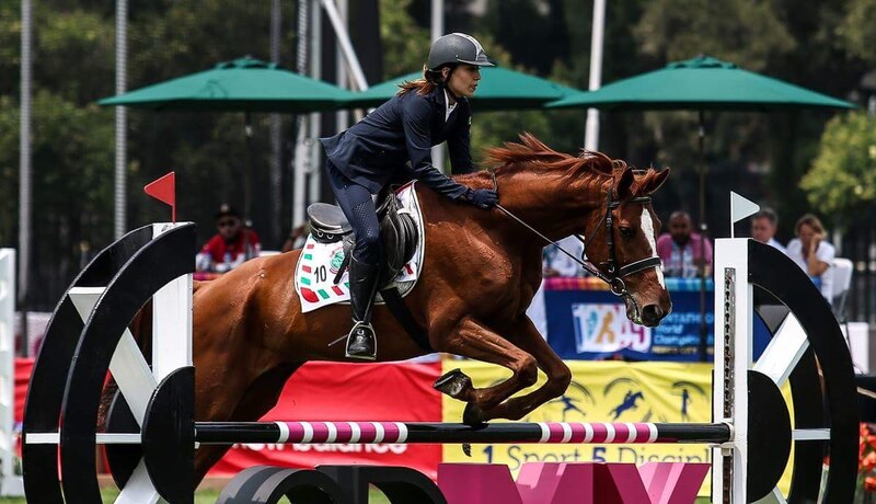 Jinetes ecuestres saltando obstáculos en una competencia.
