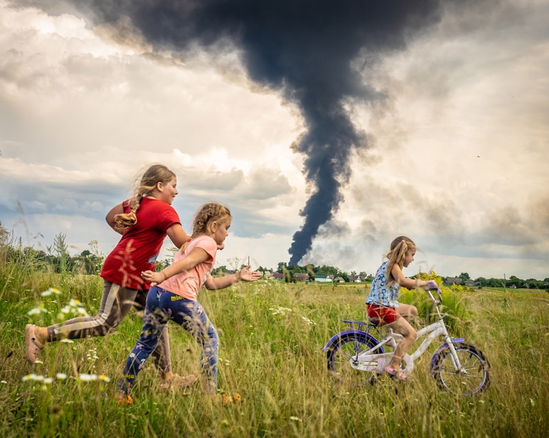 Niñas corriendo en un campo con humo negro en el fondo