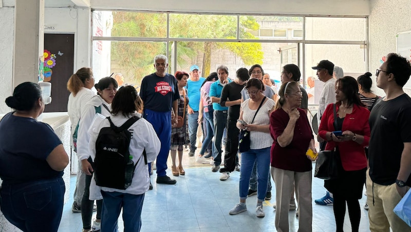 Larga fila de personas en el interior de un edificio