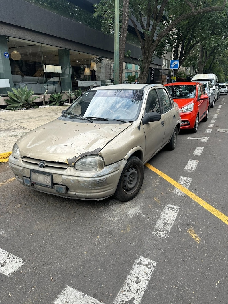 Un coche viejo y oxidado aparcado en la calle