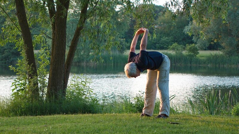 Hombre mayor haciendo yoga al aire libre