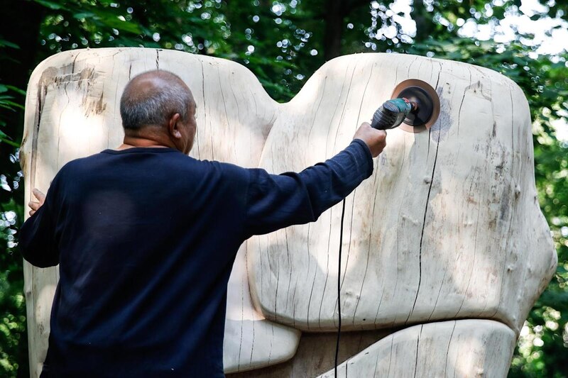 Un escultor trabaja en una escultura de madera al aire libre
