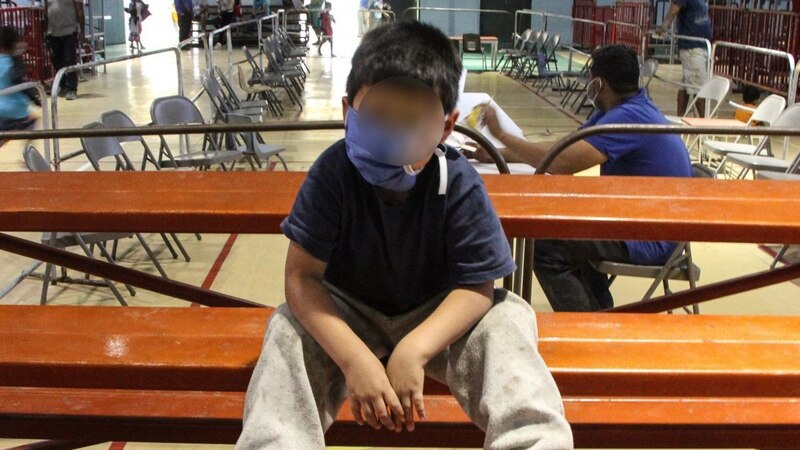 Niño hondureño espera en una silla para recibir asistencia humanitaria