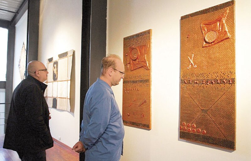 Dos hombres observan una obra de arte en una galería.