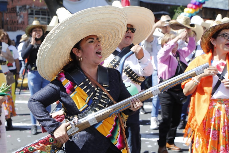 Mujer mexicana con sombrero y traje tradicional dispara un arma