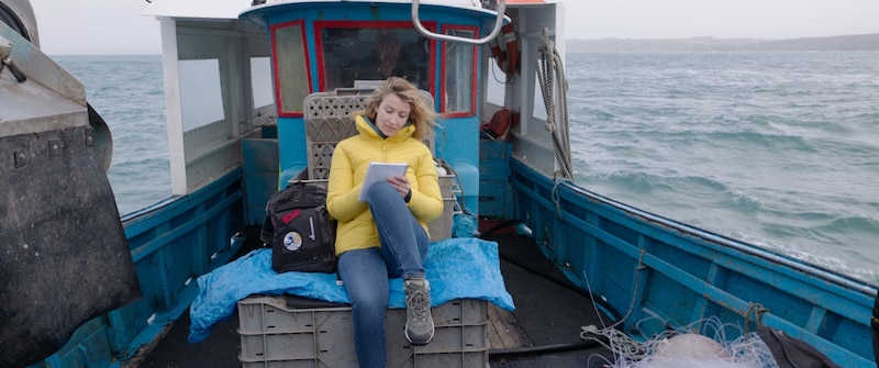 Mujer escribiendo en un barco