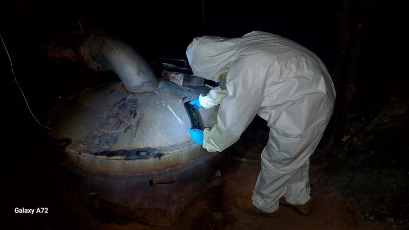 Un científico en un traje protector inspecciona un tanque industrial