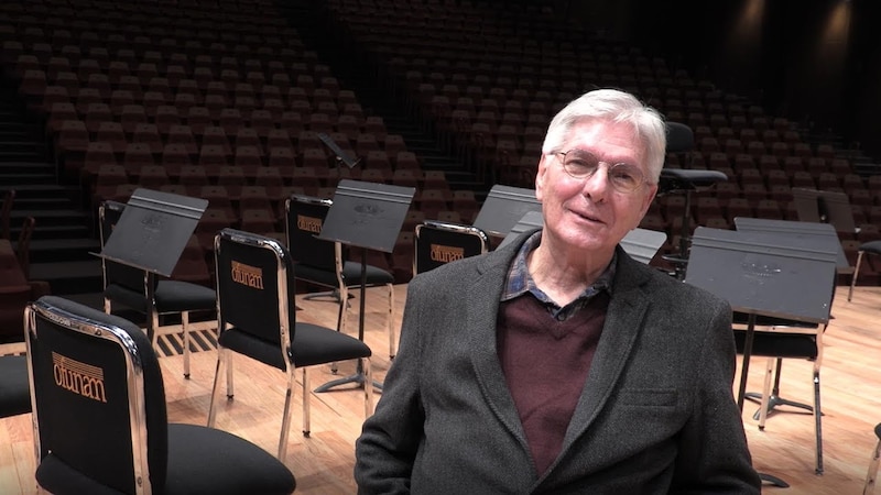 El director de orquesta Zubin Mehta sonríe en el escenario de un auditorio vacío