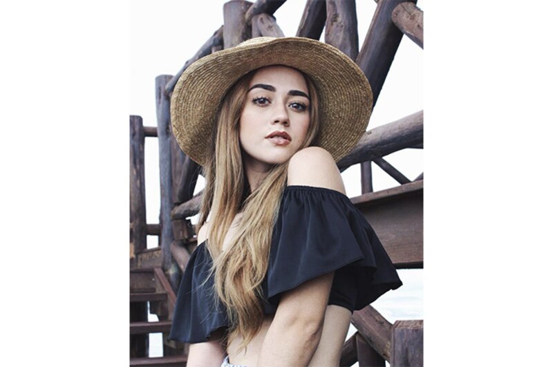 Mujer joven con sombrero de paja y hombros descubiertos