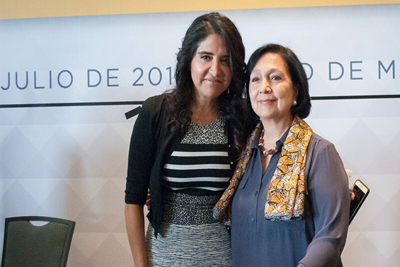 Dos mujeres sonríen y se abrazan en una conferencia.