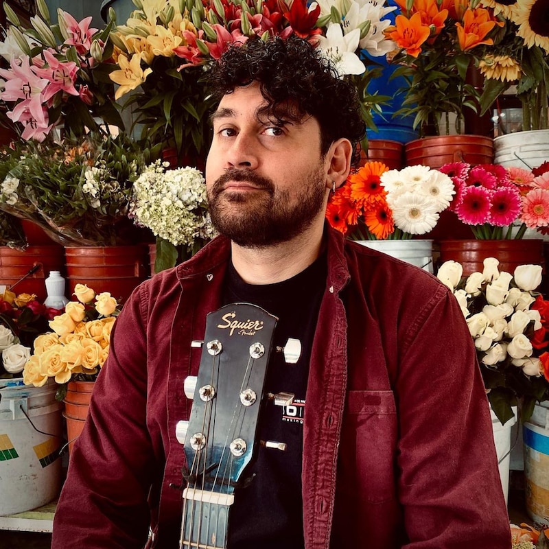 Cantante mexicano con guitarra en un mercado de flores