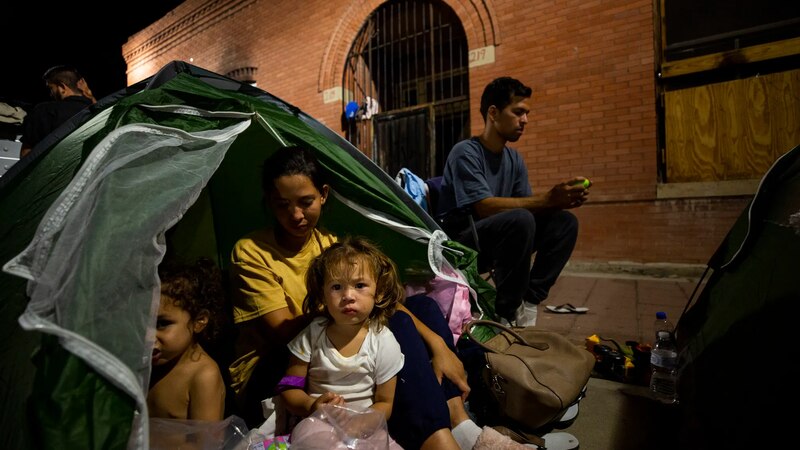 Madre e hijos migrantes esperan en la frontera