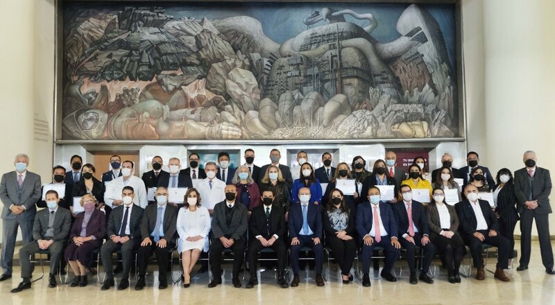 Un grupo de personas posando para una foto frente a un mural.
