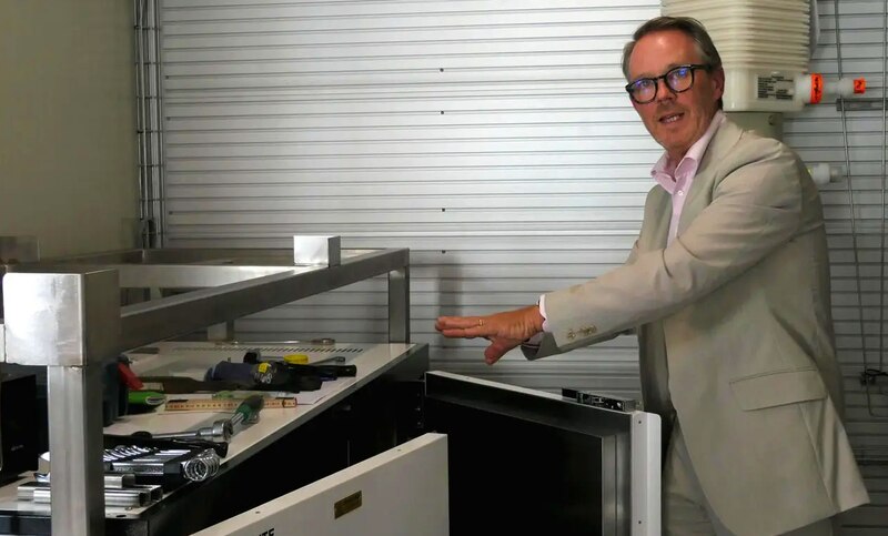 Científico en bata blanca muestra un refrigerador de laboratorio
