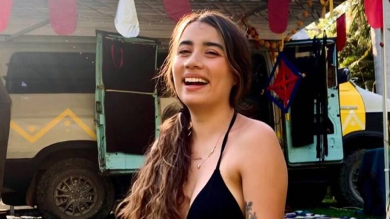 Mujer joven sonriendo frente a una furgoneta camperizada