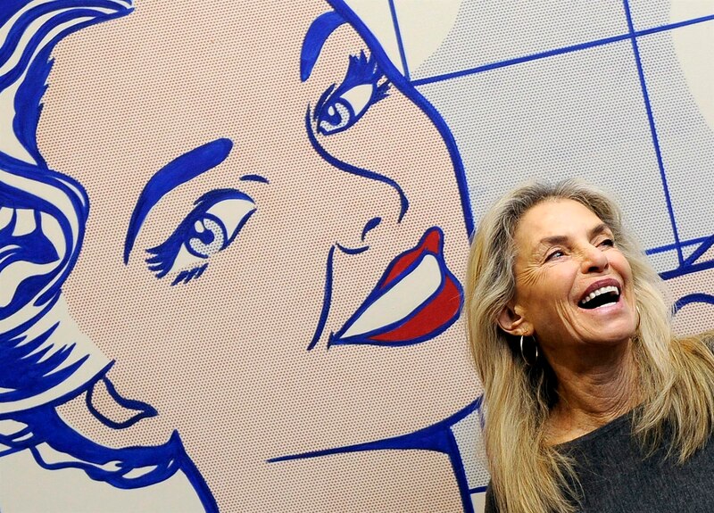 La artista pop Rosalía Mera sonriendo junto a su obra.