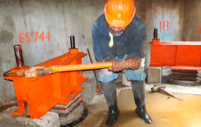 Trabajador de la construcción usando una llave para ajustar una tuerca en una viga de acero.