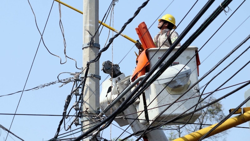 Un trabajador de la compañía eléctrica repara una línea eléctrica.