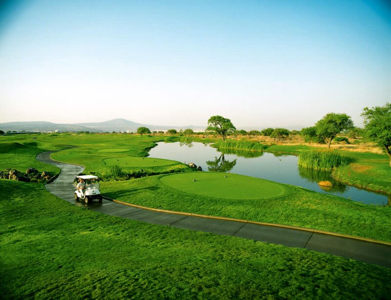 Campo de golf con un lago y un carrito de golf