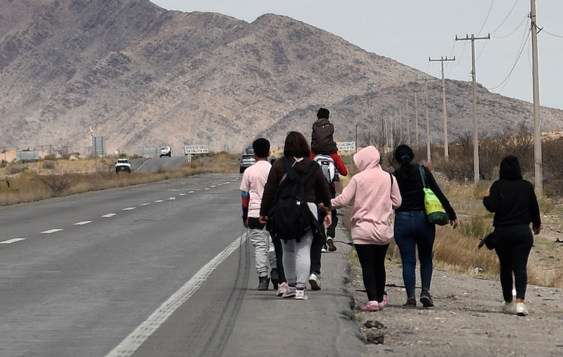 Un grupo de personas camina por una carretera en una zona rural.