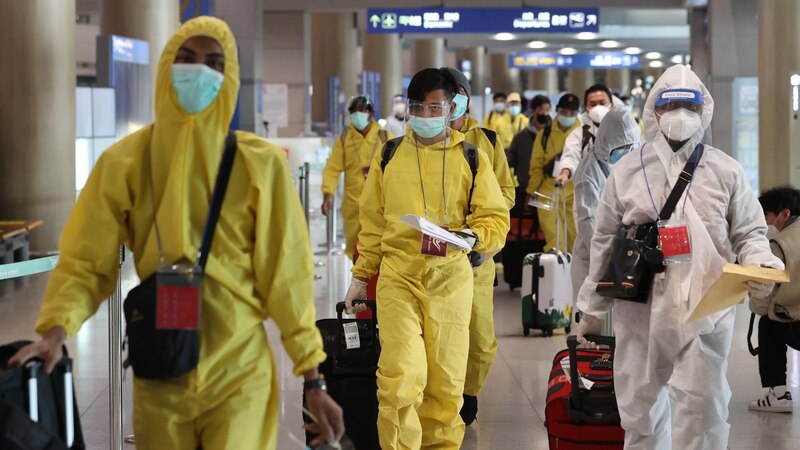 Pasajeros con trajes de protección en el aeropuerto