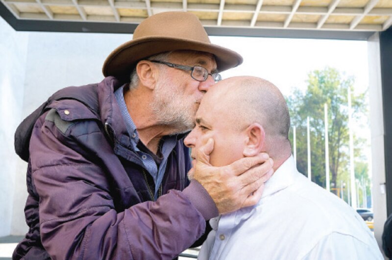 Un hombre mayor besa en la frente a un hombre más joven