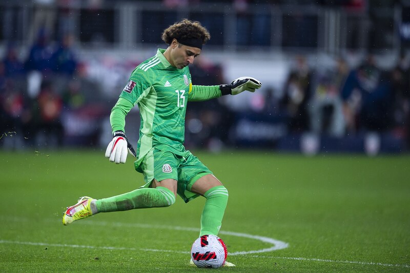 El portero mexicano Guillermo Ochoa despeja el balón durante un partido de fútbol.