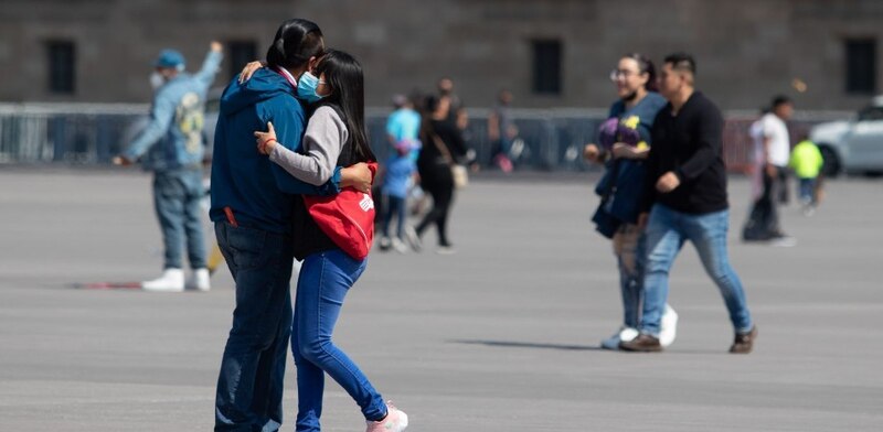 Un abrazo entre dos personas con mascarillas