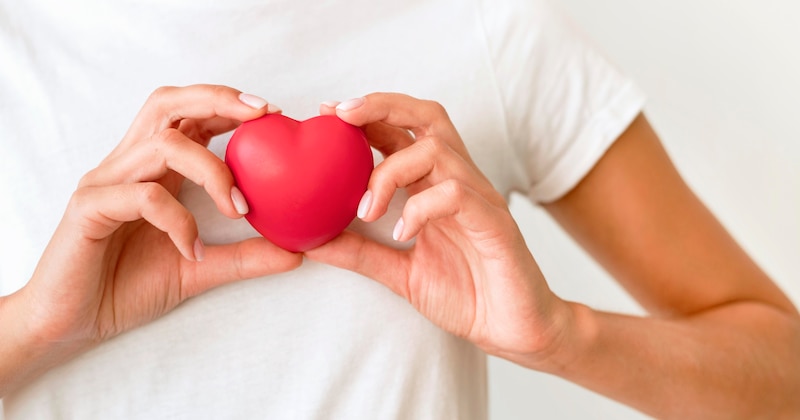 Mujer sosteniendo un corazón rojo en sus manos