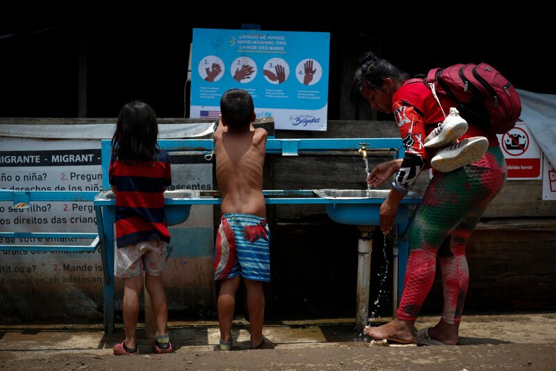 Madre e hijos migrantes se lavan las manos en un lavabo público