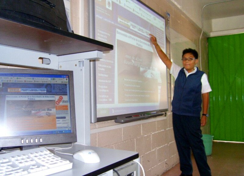 Niño usando una pizarra digital en el aula