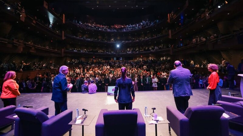 Políticos en un escenario dando un discurso ante una multitud.