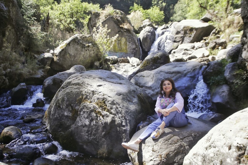 Mujer sentada en una roca en medio de un río