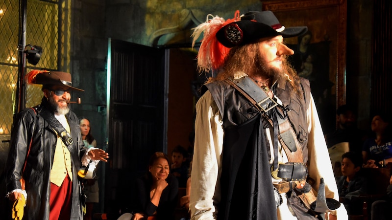 Actores vestidos de época representan una escena de piratas en un teatro