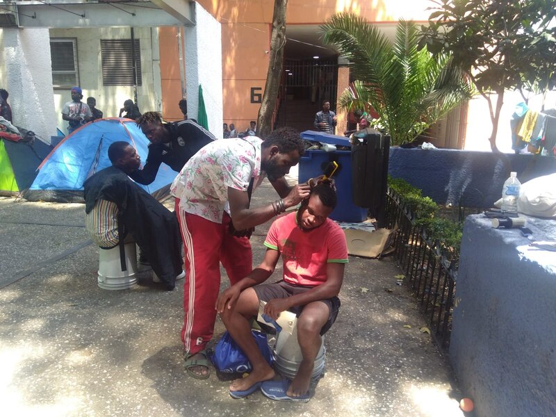 Un barbero corta el pelo a un hombre en un campamento improvisado