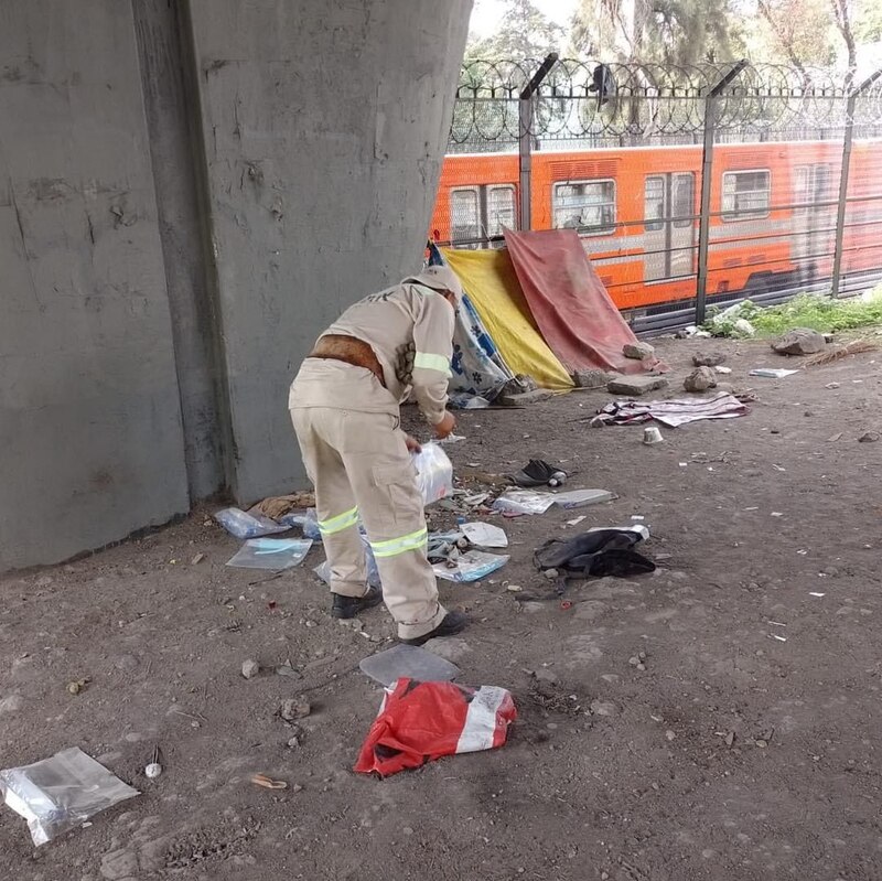 Un hombre recogiendo basura en las vías del tren