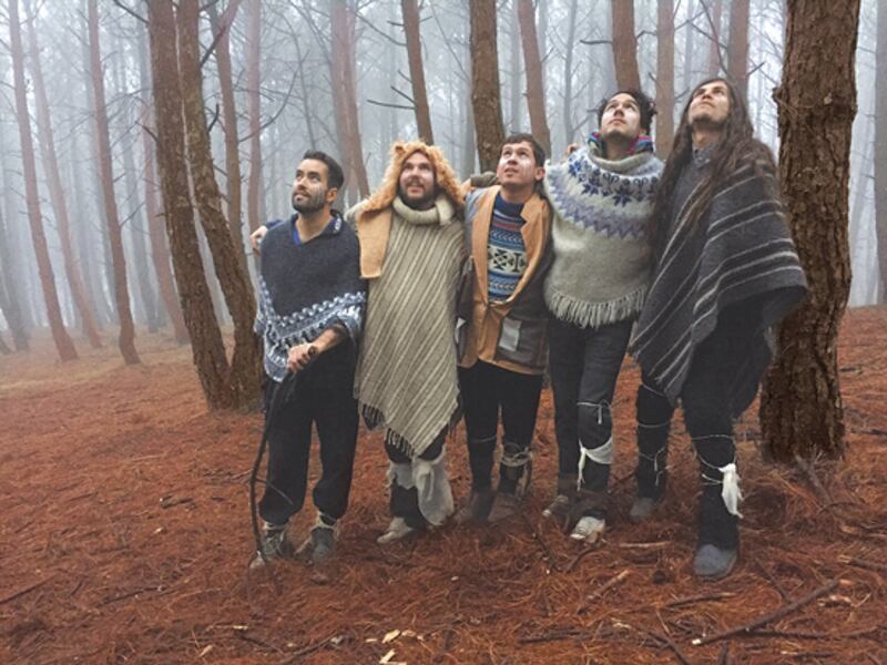 Un grupo de hombres vestidos con ropa tradicional camina por un bosque.