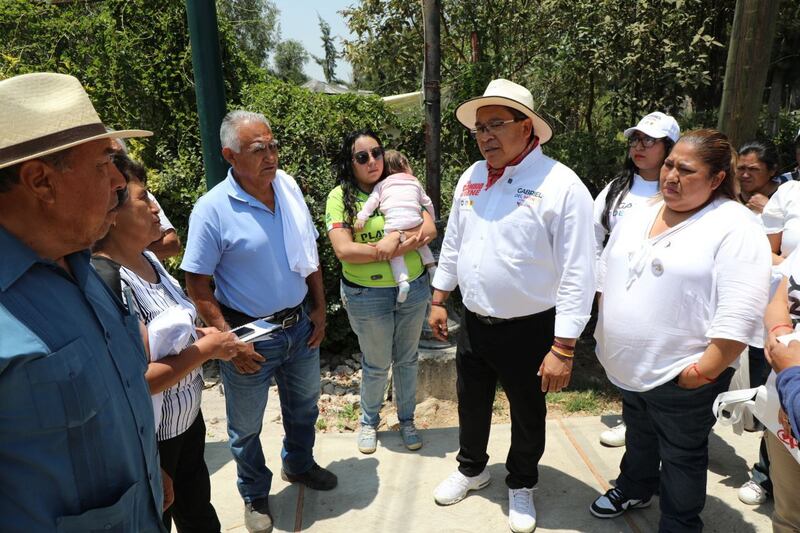 El candidato Gabriel Boric conversa con un grupo de personas en una plaza pública.