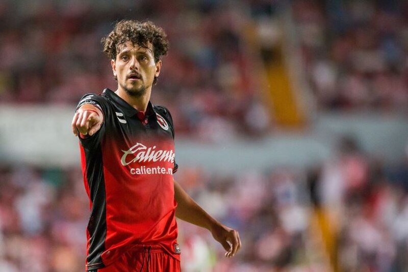 Jugador de fútbol americano en uniforme rojo y negro señala con el dedo