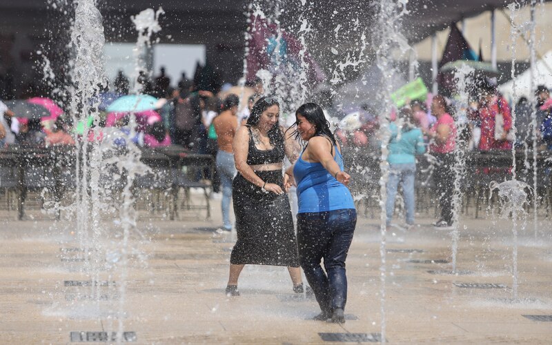 Mujeres bailando bajo una fuente