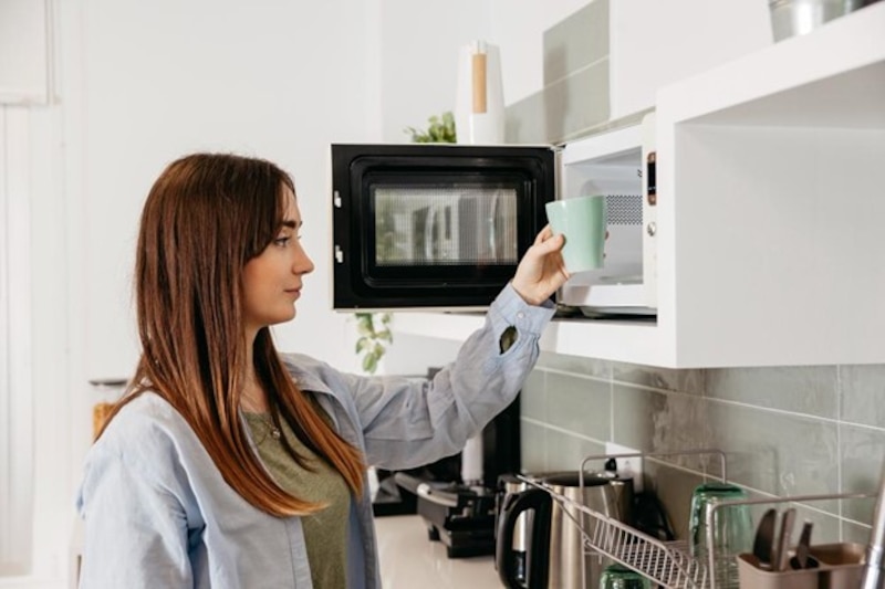 Persona introduciendo una taza a un horno de microondas