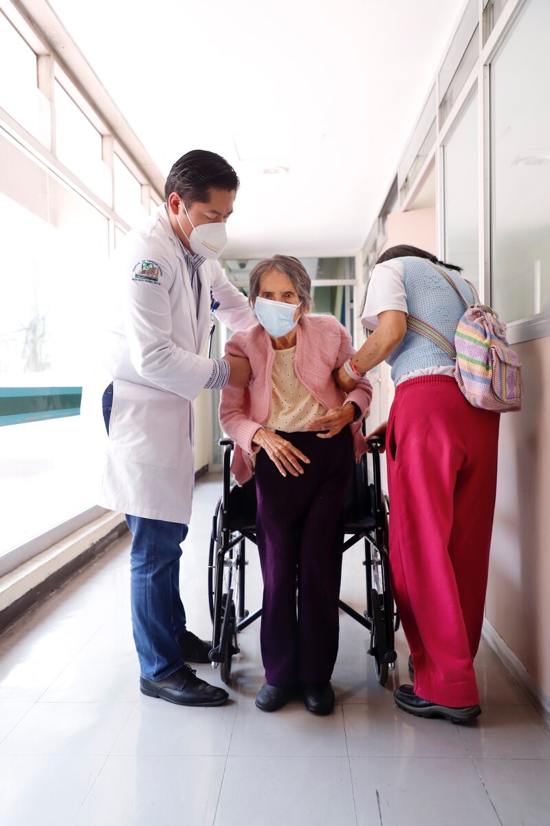 Doctor ayudando a una paciente anciana en silla de ruedas