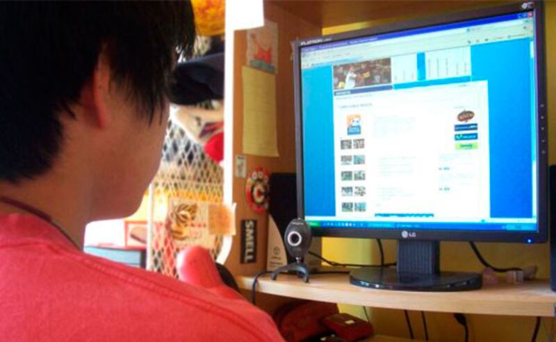 Un joven mira su computadora