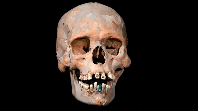 Cráneo humano con una piedra preciosa en la boca